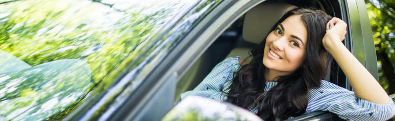 teenaged girl sitting in her car looking out of her window